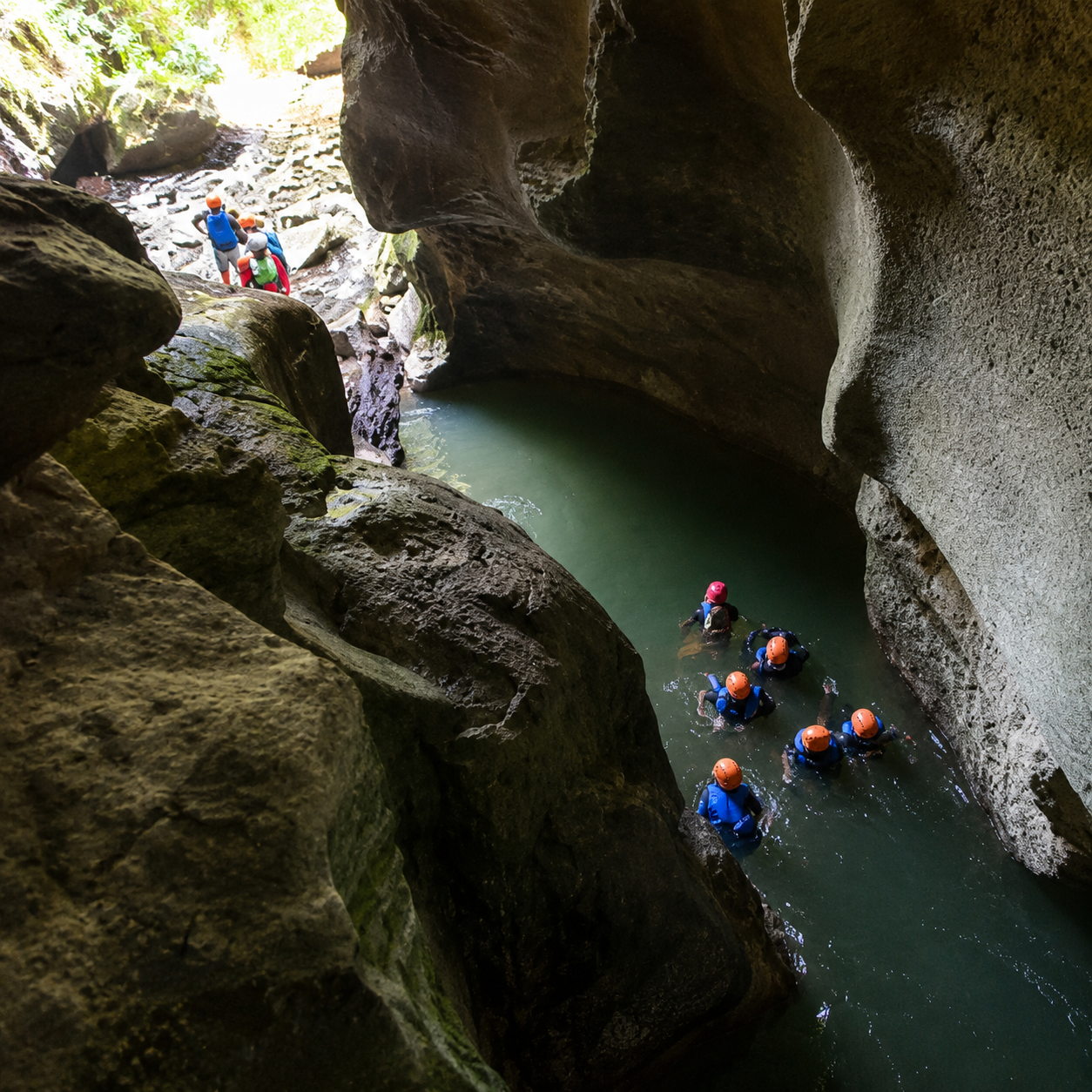 Guests swimming through the cave canyon in life jackets and helmets