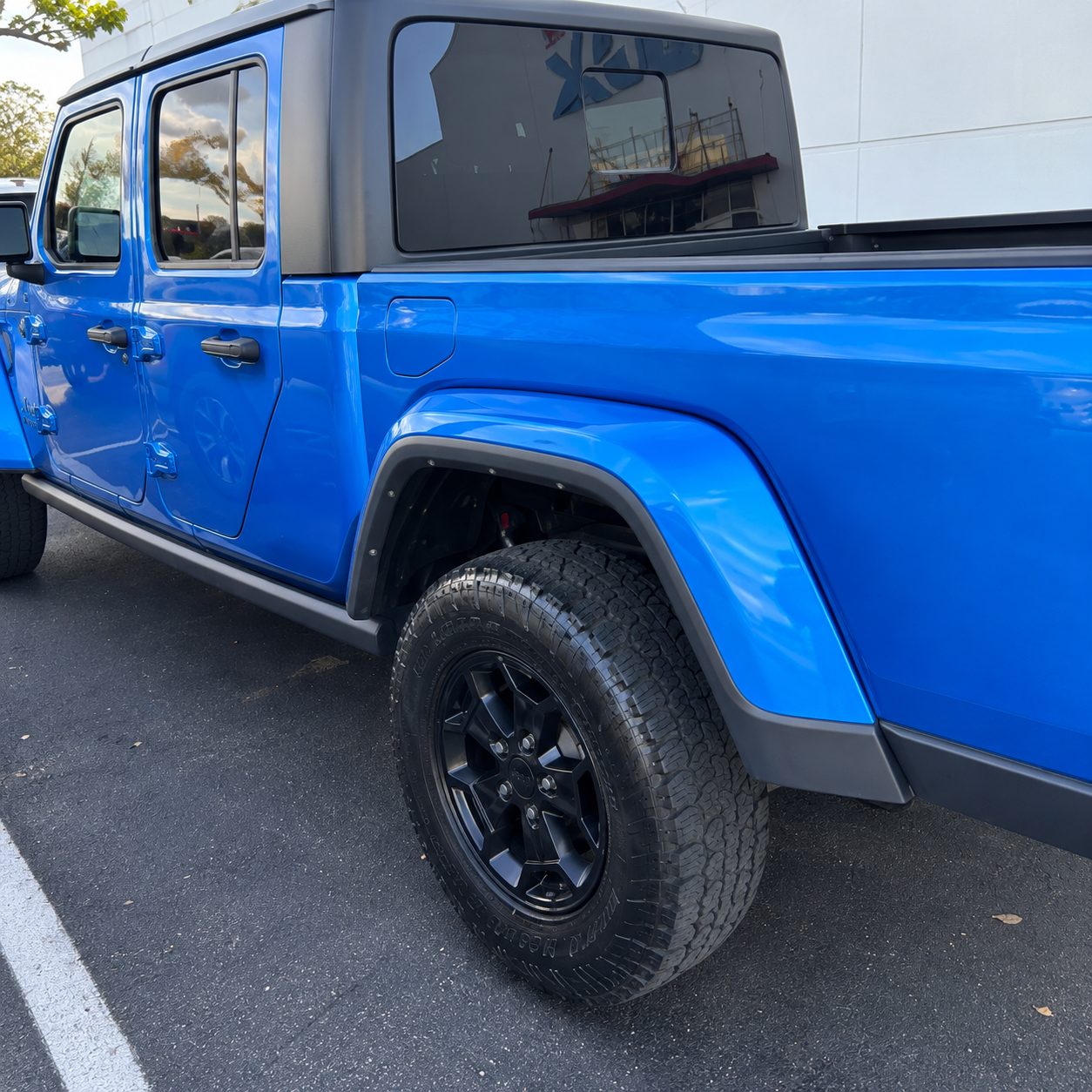 Side profile of the blue Jeep four-door rental with hardtop and all-terrain tires