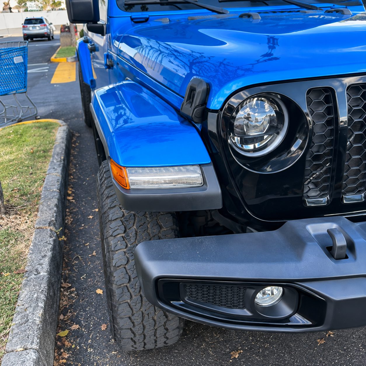Close-up of the blue Jeep front end, LED headlight and seven-slot grille