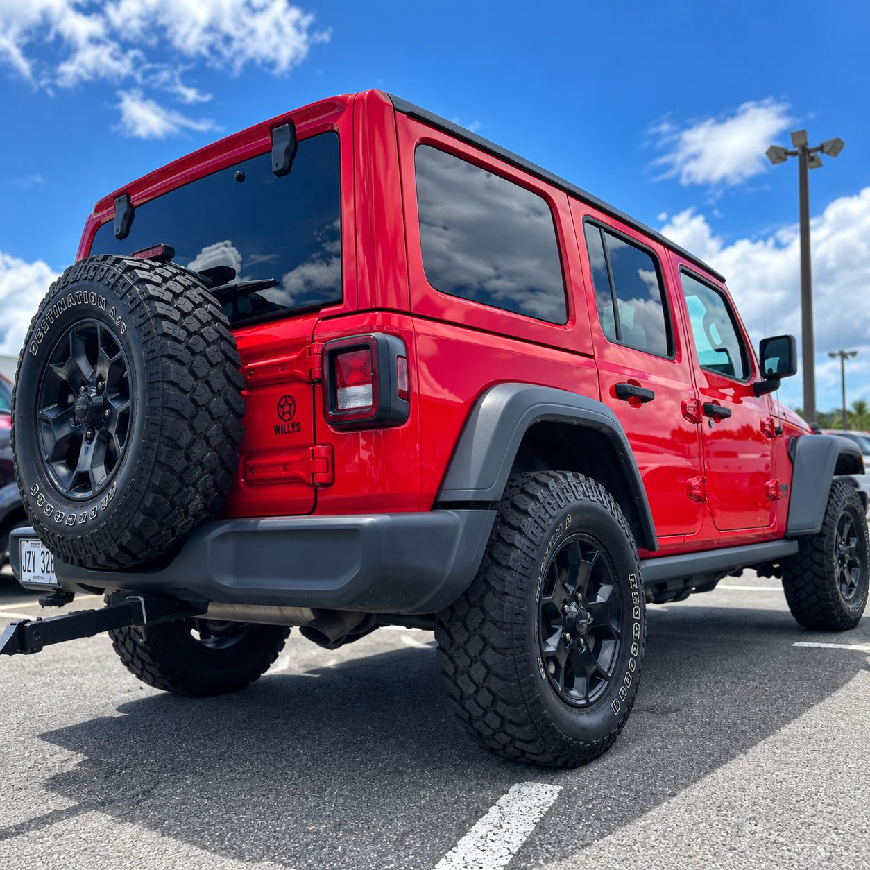 Rear three-quarter view of the red Jeep Willys showing the four-door body and all-terrain tires