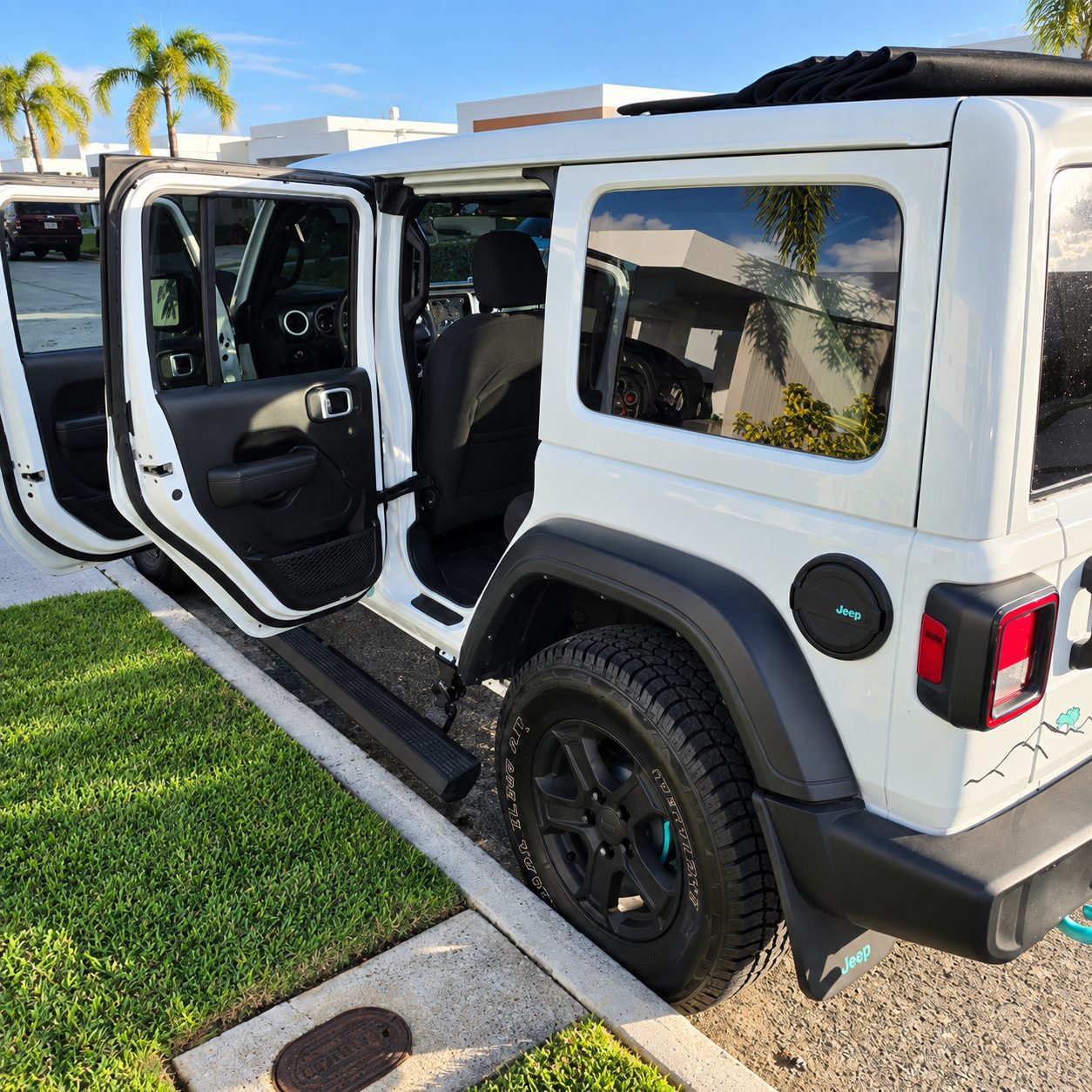 Doors open on the white Jeep Willys showing the four-door interior and rear cargo area