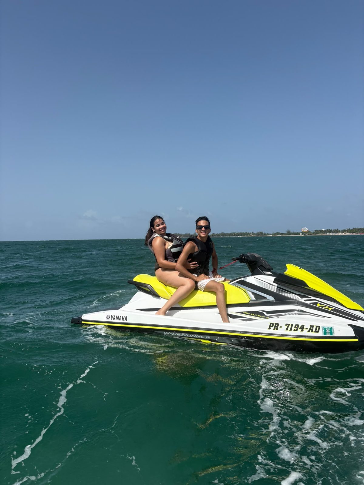 Couple wearing life jackets on a Yamaha WaveRunner jet ski rental off the Isla Verde coast in Puerto Rico
